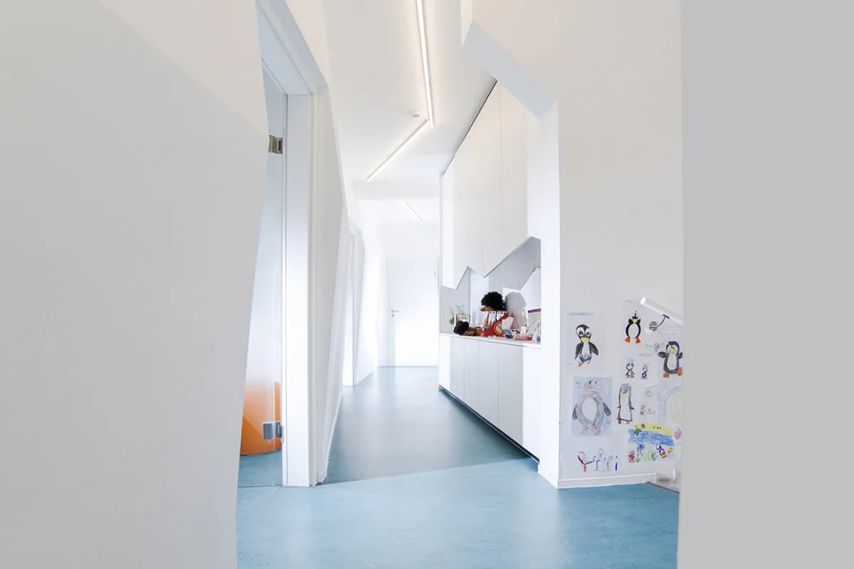 Weißer Flur mit blauem Boden und Kinderzeichnungen an der Wand