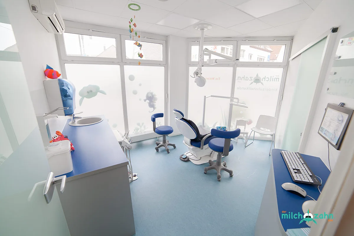 Behandlungszimmer mit blauen Stühlen und Unterwasser-Motiven an den Scheiben